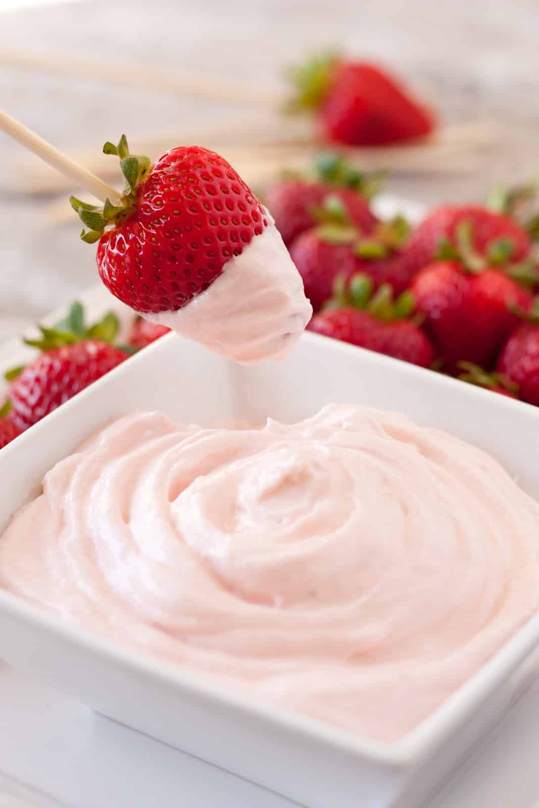 Fruit Dip in a serving bowl with strawberry dipped in a skewer.