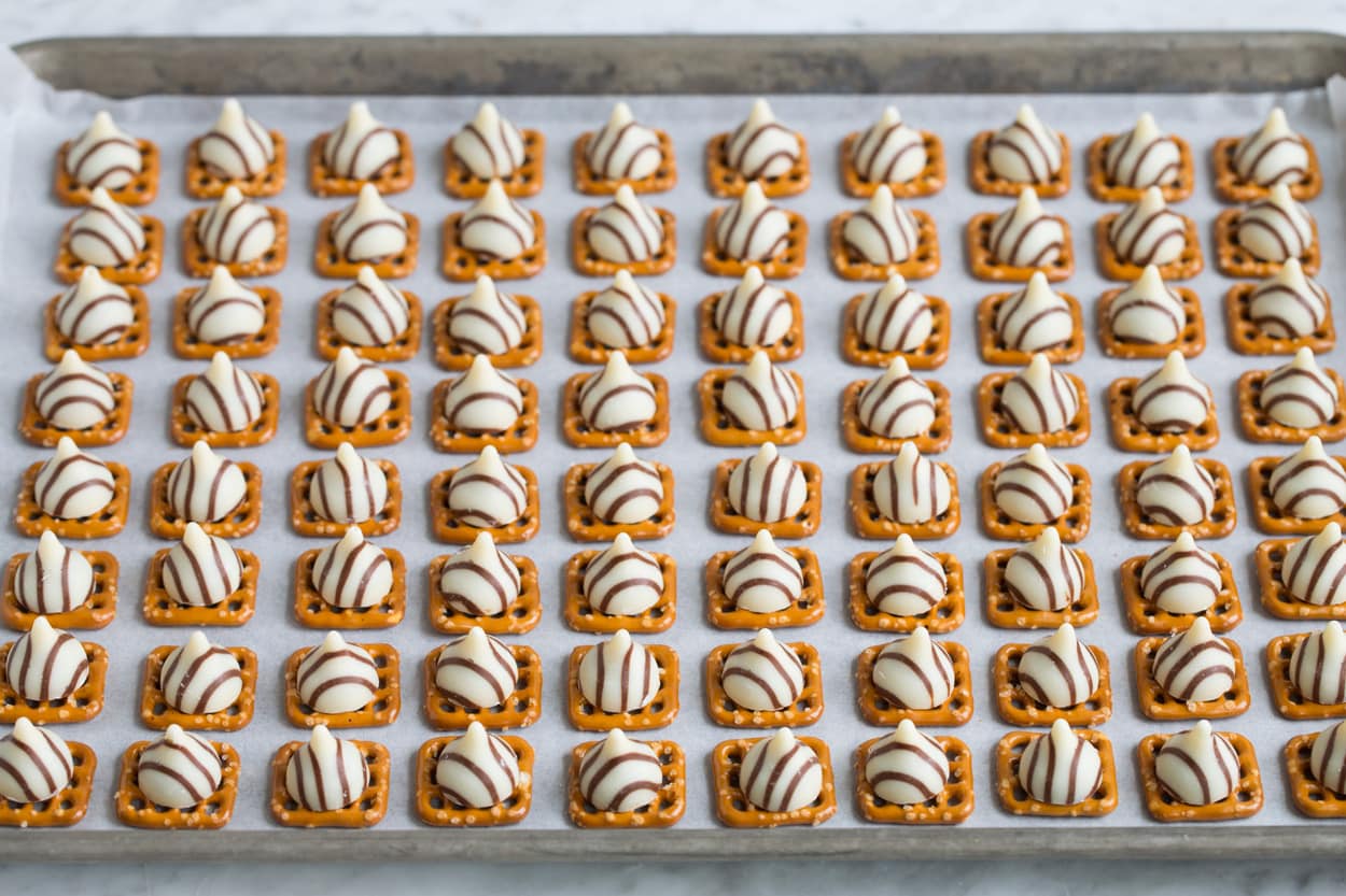 Adding hugs to pretzels on baking sheet.