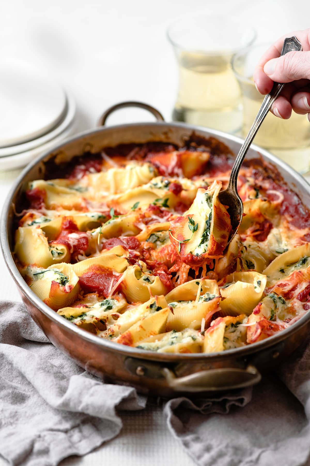Scooping one spinach and cheese stuffed shell from the casserole dish.