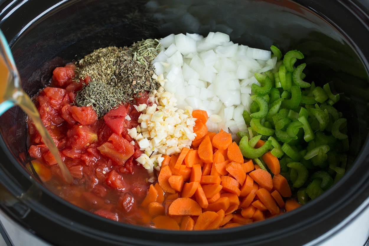 Showing how to make minestrone soup. Adding vegetables to crockpot along with broth.