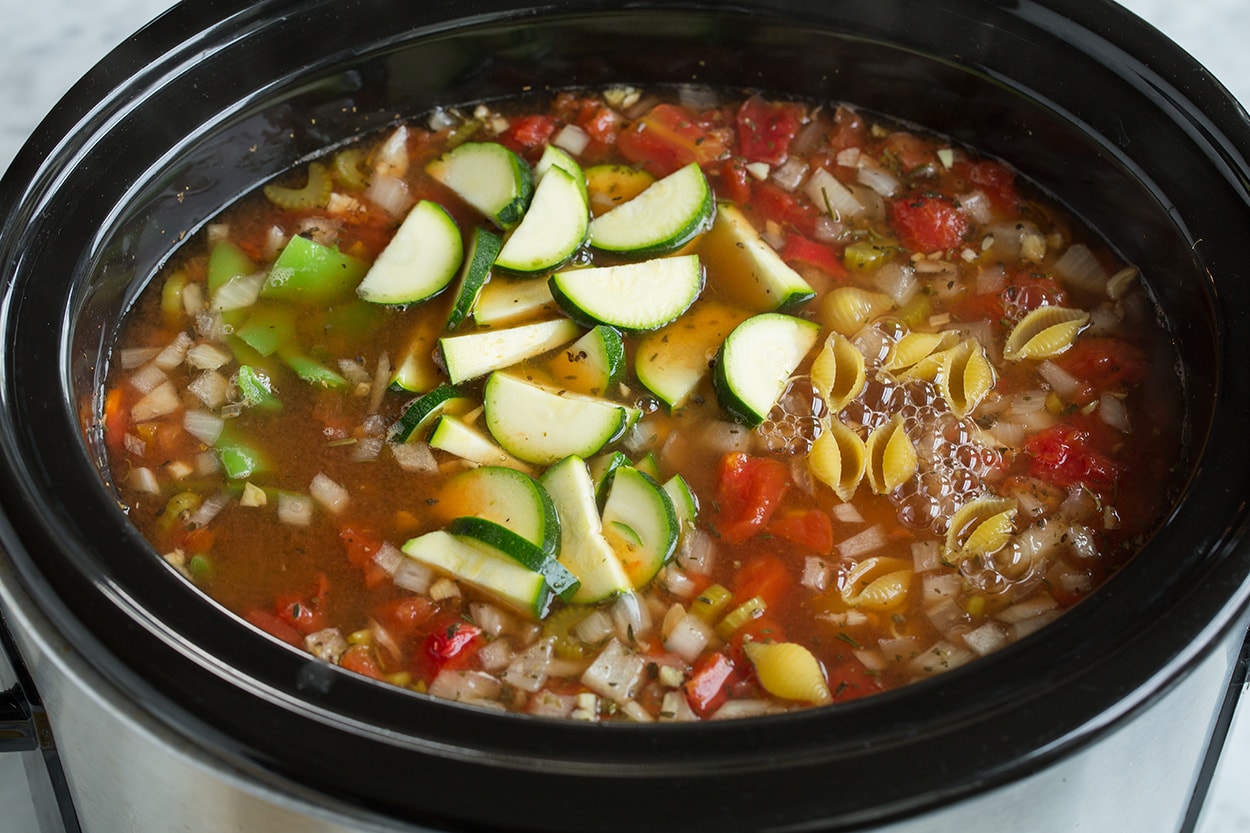 Adding zucchini, beans and pasta to slow cooker. 