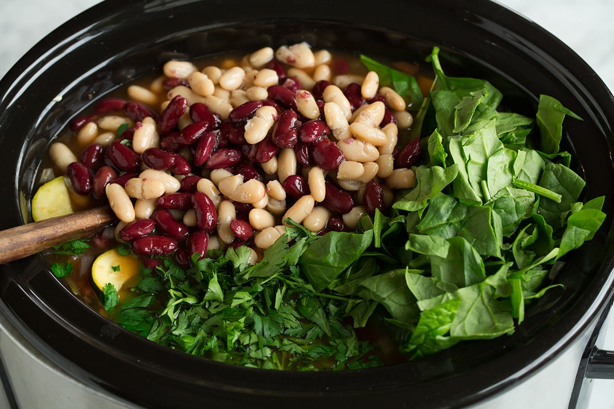 Adding beans, spinach and parsley to minestrone.