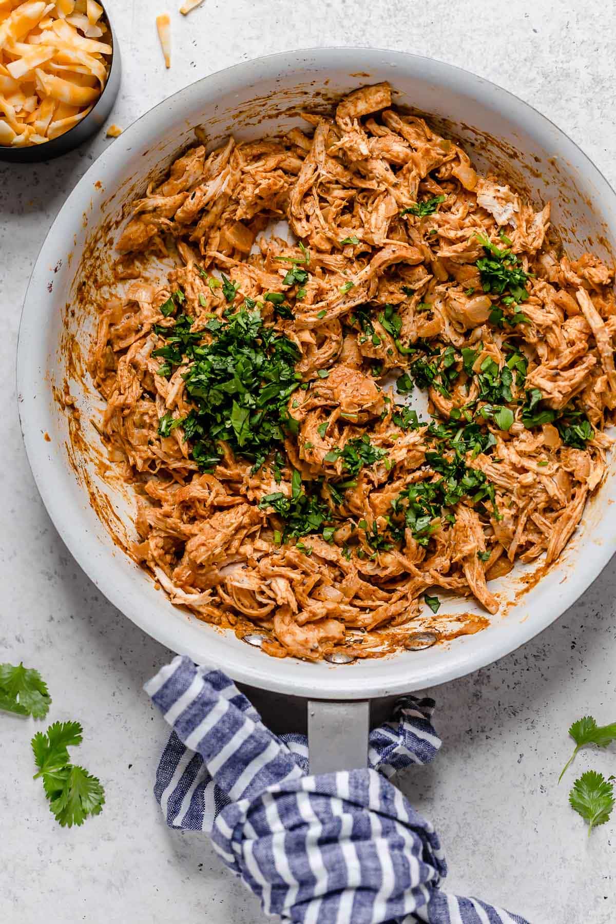 Chicken Taquito filling in a white skillet, garnished with cilantro on top.