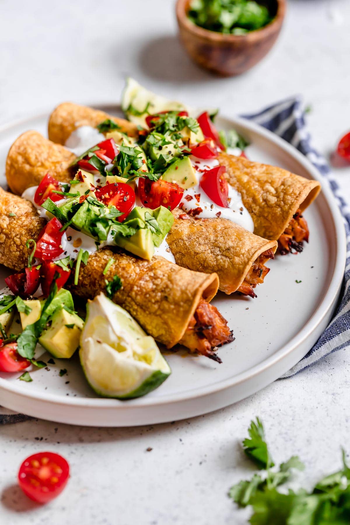 Close up image of taquitos on a white serving plate.