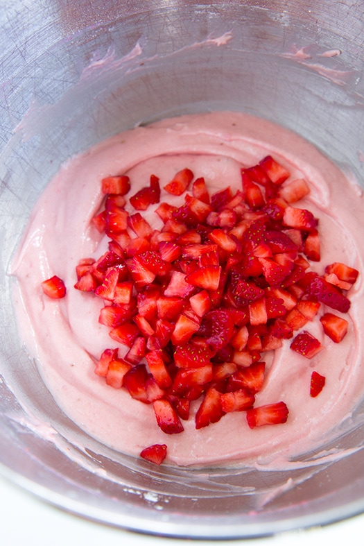 An overhead shot of strawberry cupcake batter in a bowl with fresh diced strawberries