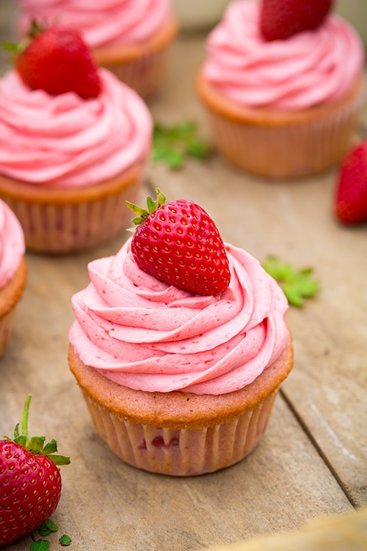 Strawberry Cupcakes with Strawberry Buttercream Frosting sitting on a wooden surface