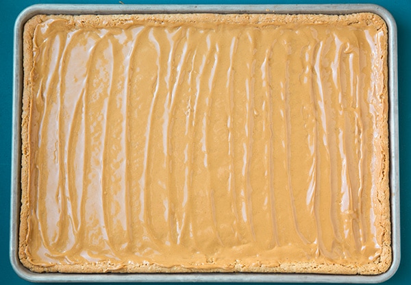 Spreading peanut butter over warm peanut butter bars.
