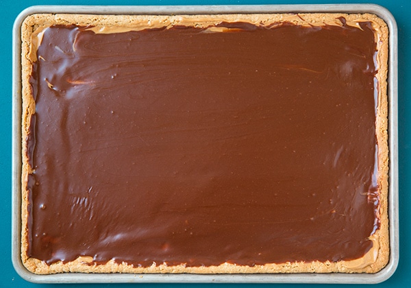 Adding chocolate frosting to peanut butter bars.