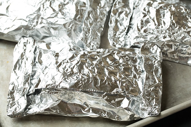 Wrapping salmon in foil packets and setting on baking sheet to bake.