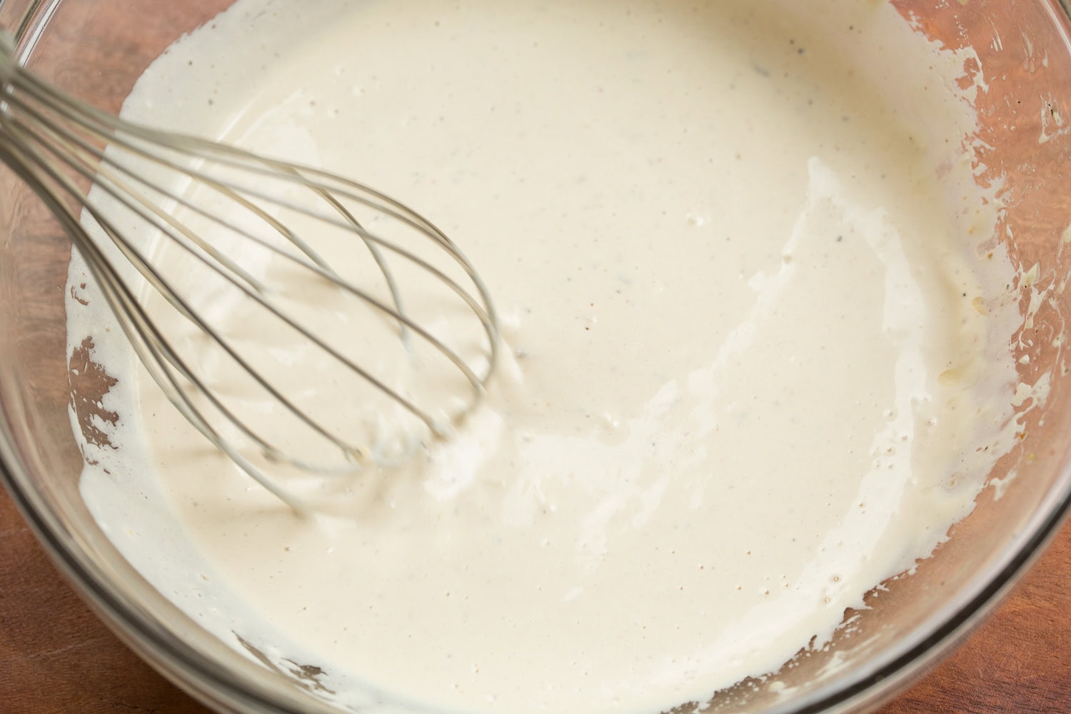 Caesar dressing in glass mixing bowl shown after mixing.