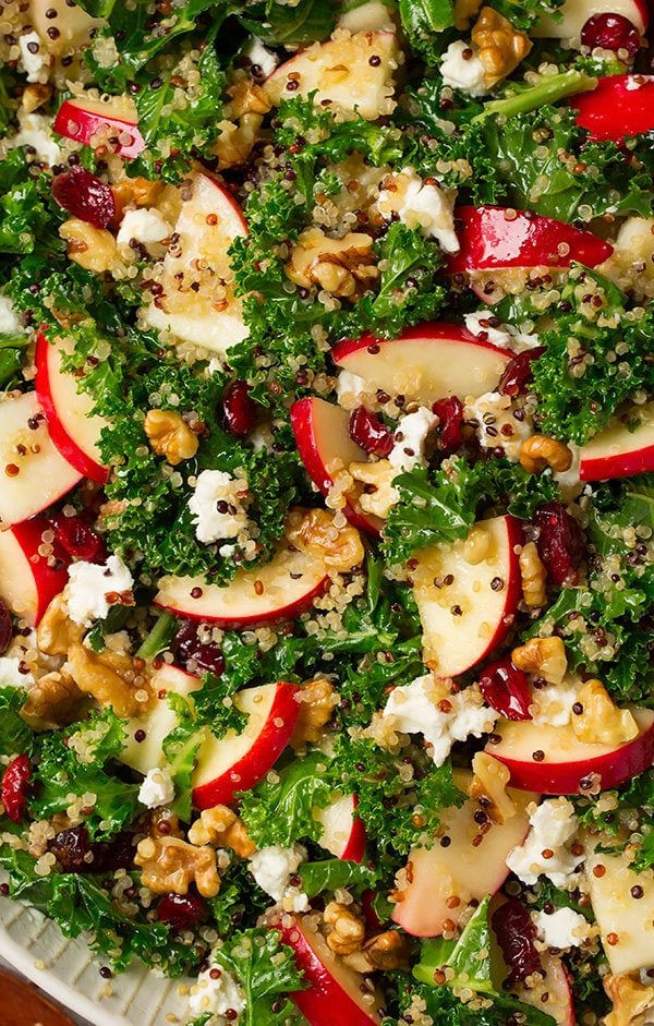 Close up image of kale salad with apples, quinoa, goat cheese and walnuts mixed in.