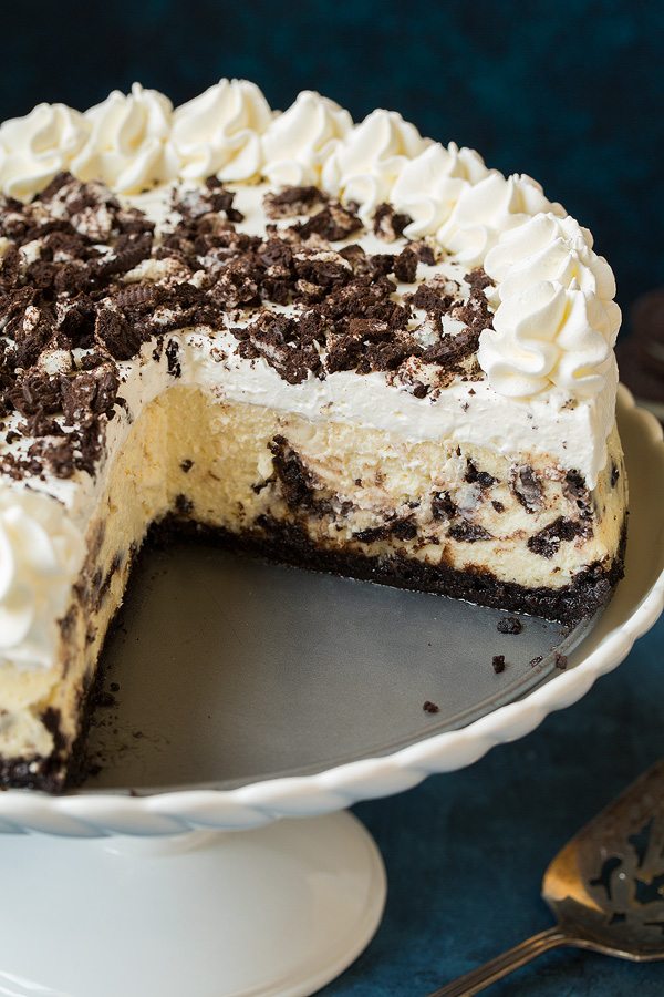Oreo cheesecake on a white cake stand.