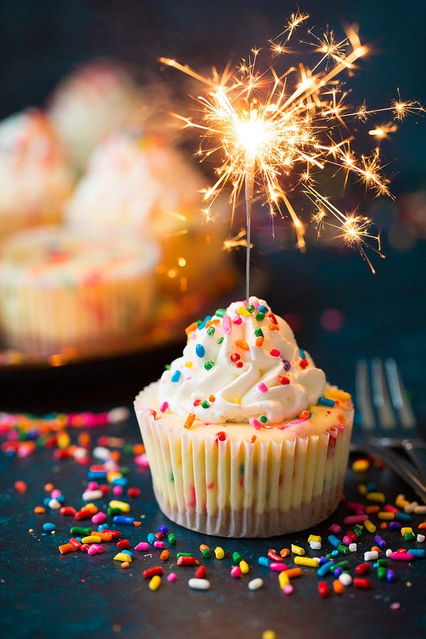 Mini birthday cheesecake with sparkler lit resting in it.