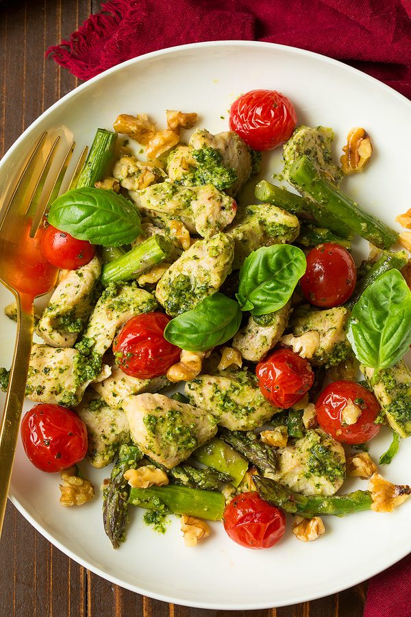 pesto chicken and asparagus bake with tomatoes on white plate