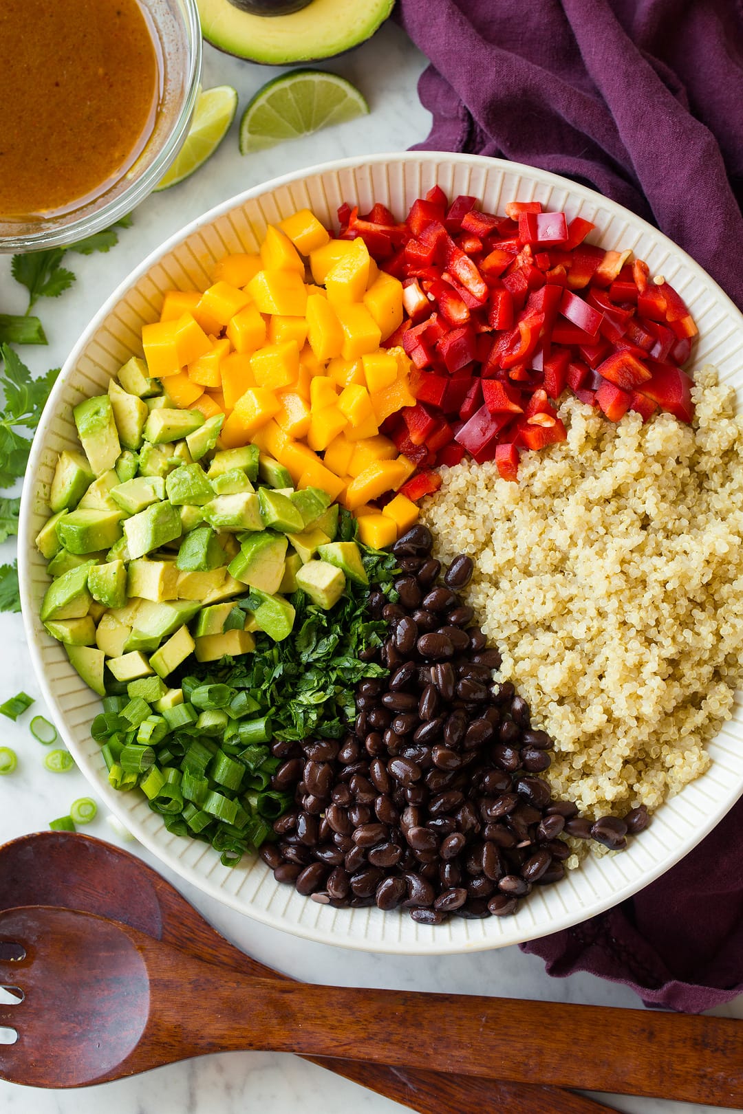 Quinoa black bean salad ingredients shown in individual portions before tossing in a white salad bowl.