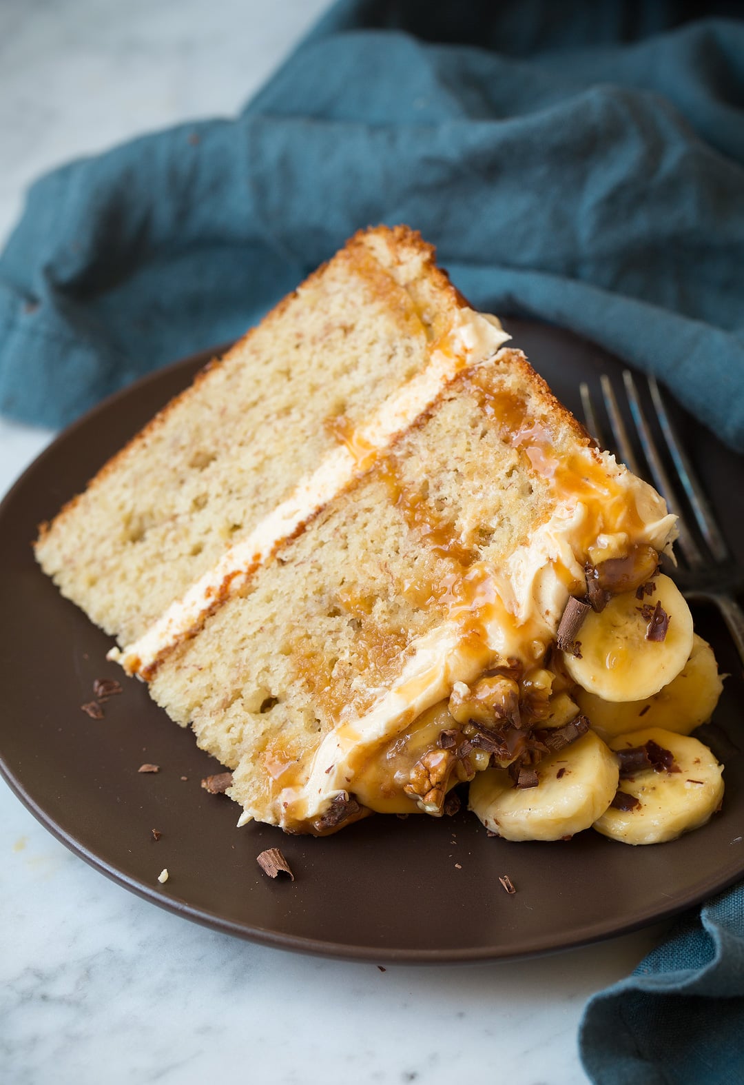 Slice of banana cake on a matte brown plate.
