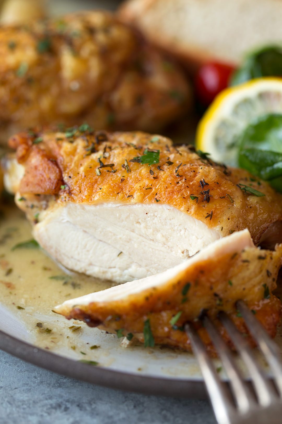 Slicing into roast chicken thigh with garlic and showing interior.