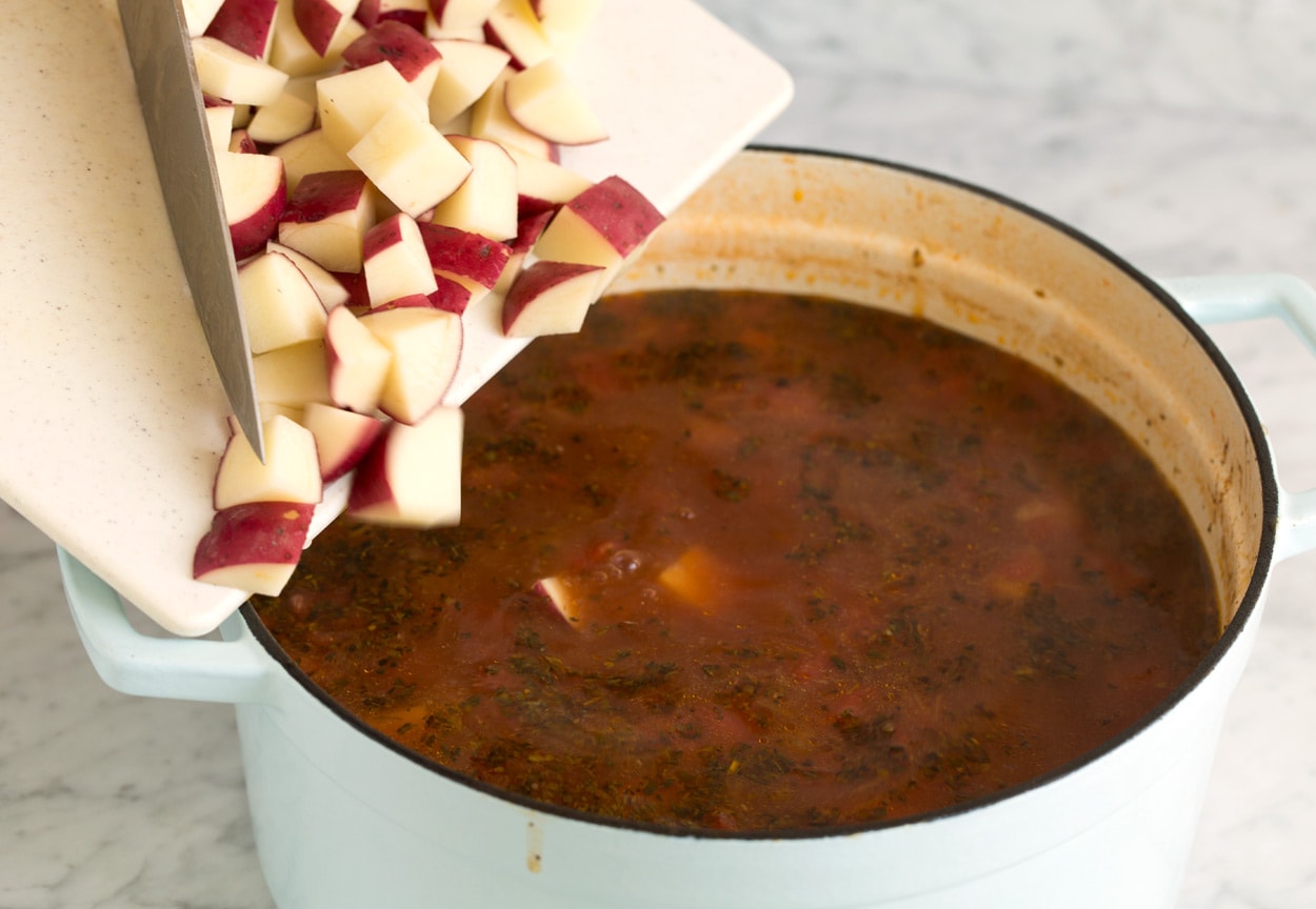 Vegetable Beef Soup adding diced potatoes to pot
