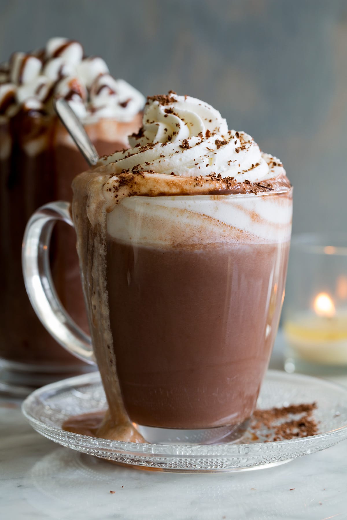 Hot Chocolate shown here in a glass mug with whipped cream and chocolate shavings on top