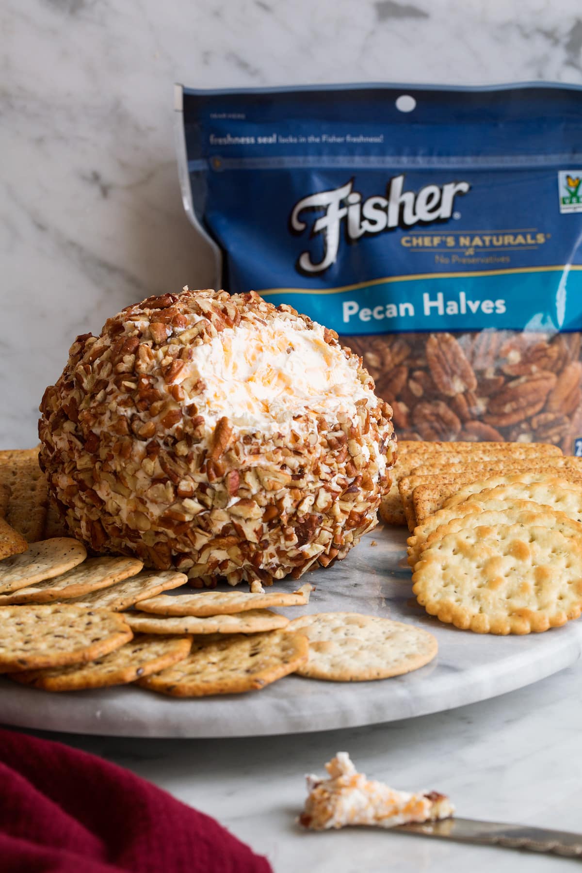 Cheese ball on a serving plate with crackers.