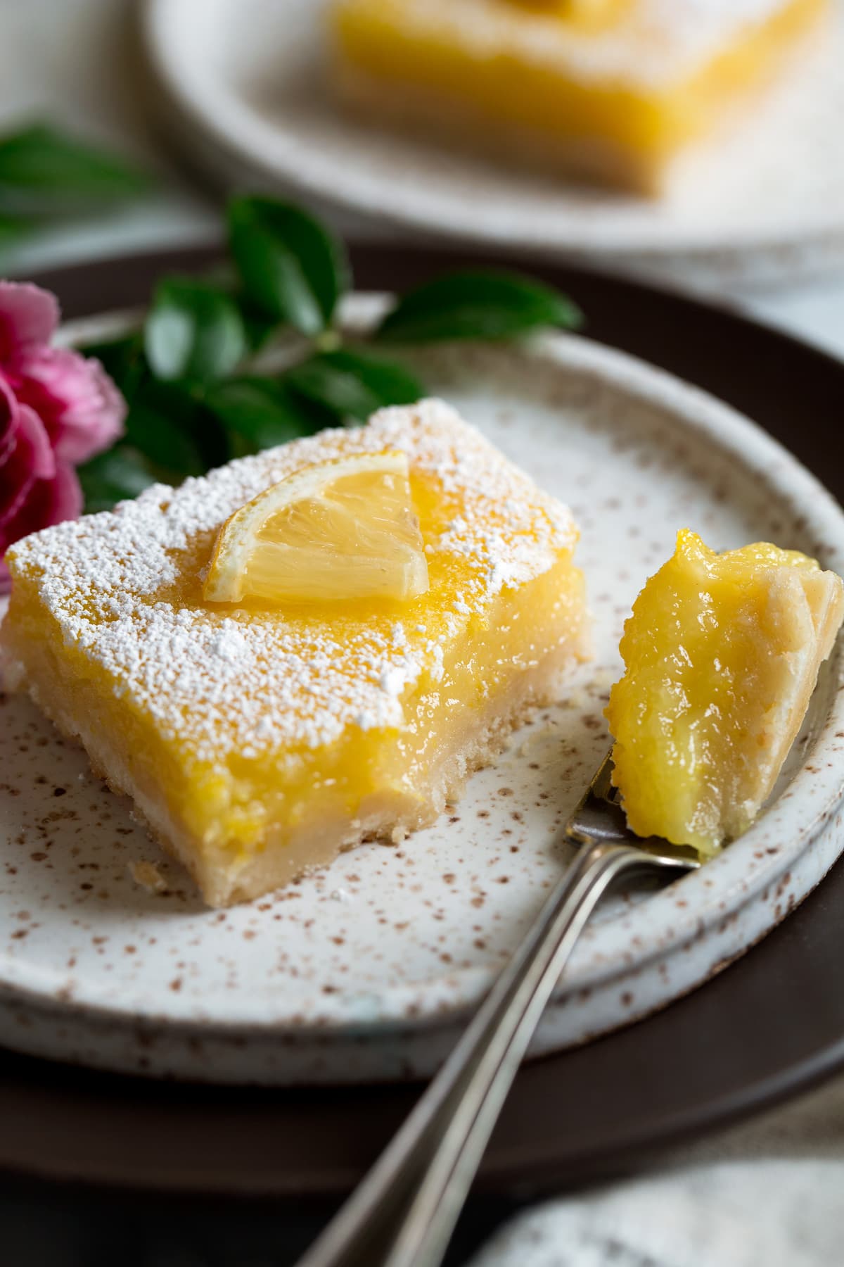Lemon bar on dessert plate with bite removed to show texture.