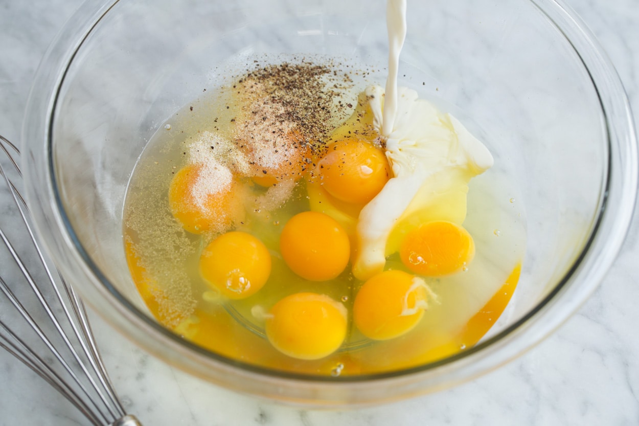 Showing how to make a frittata, mixing eggs, spices and half and half in a glass mixing bowl.