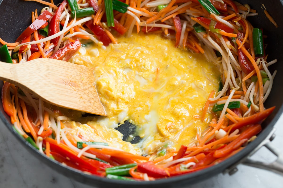 Scrambling and cooking eggs in a center of wok for pad thai.