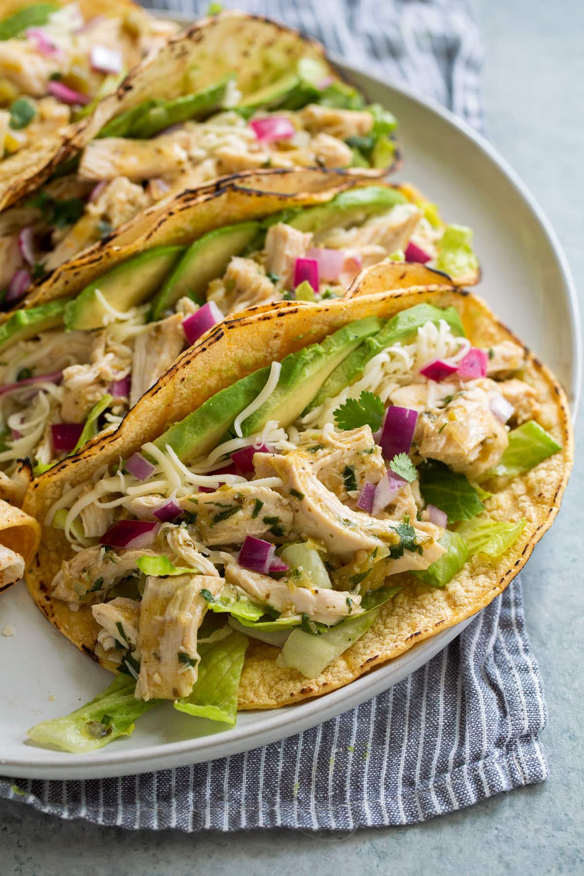 Three salsa verde chicken tacos on serving plate.