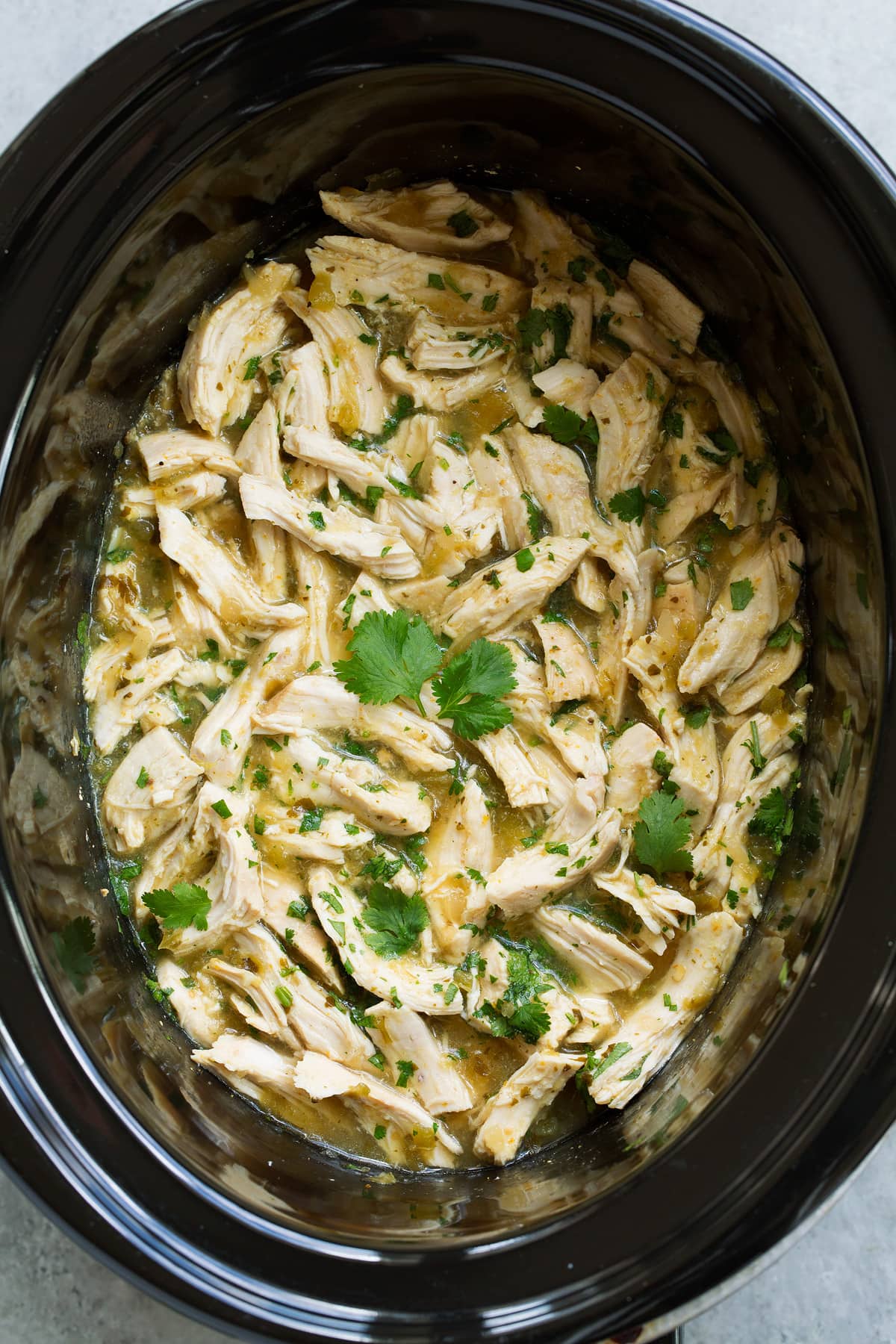 Overhead image of salsa verde chicken in a black crockpot.