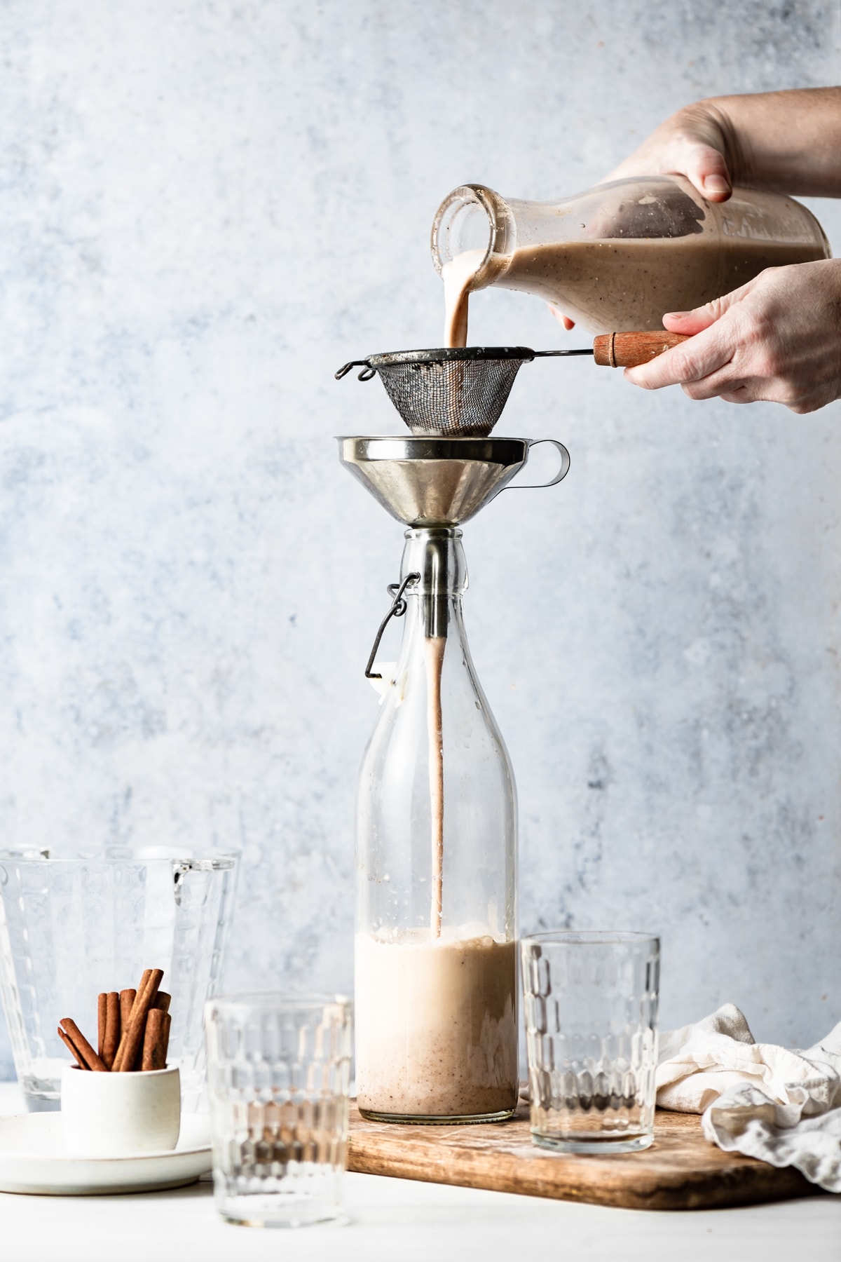Showing how to make horchata, pouring blended mixture through a fine mesh sieve into a pitcher.