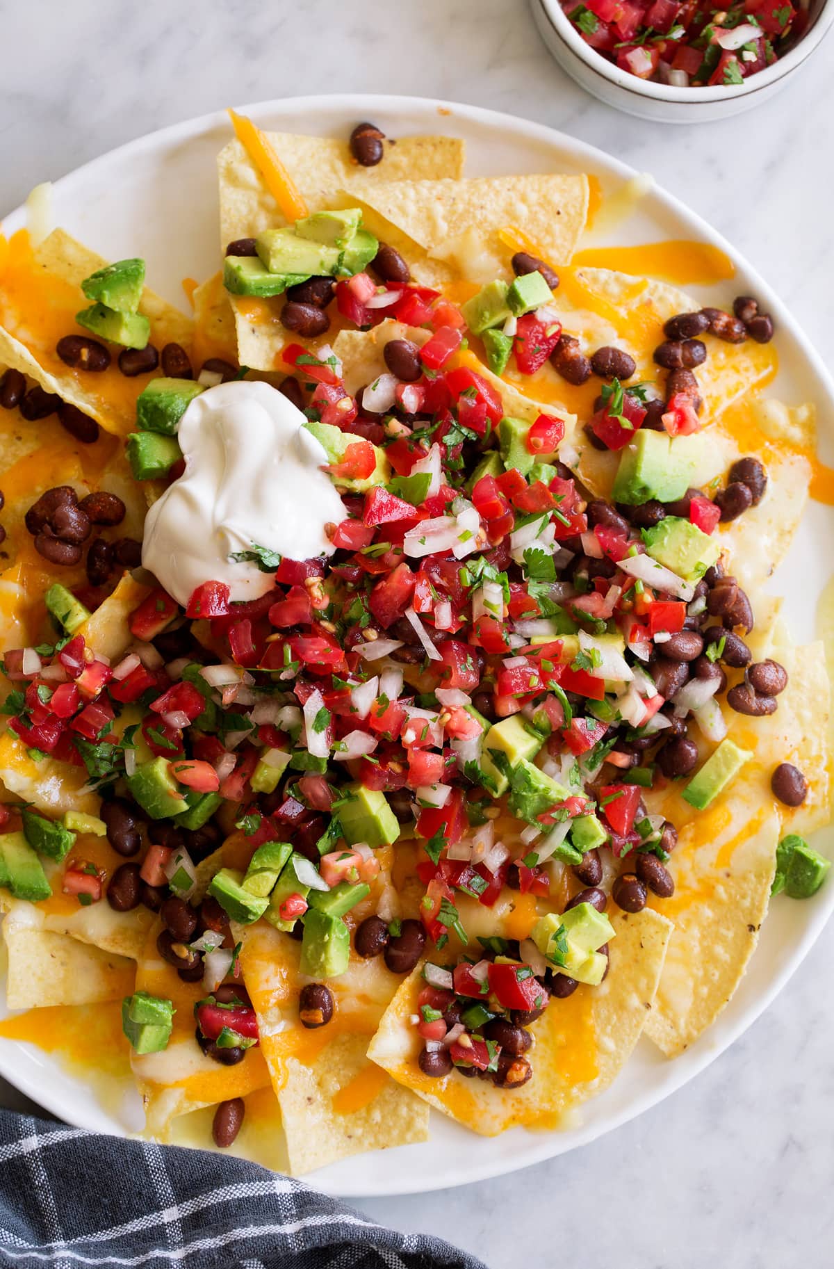 Pico de gallo over nachos along with melted cheddar, black beans, diced avocado and sour cream.