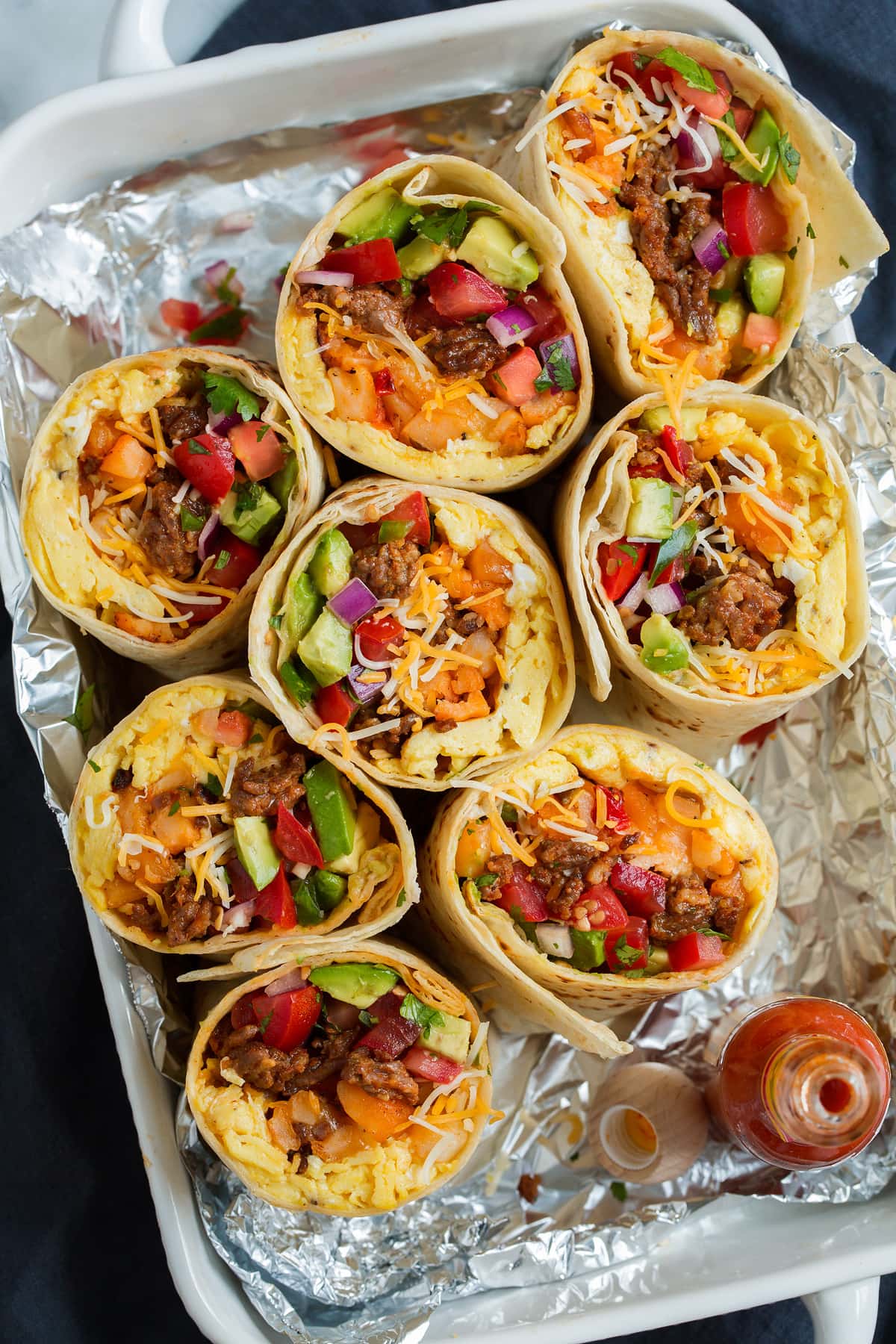 Overhead image of breakfast burritos cut in half in a serving dish lined with foil.