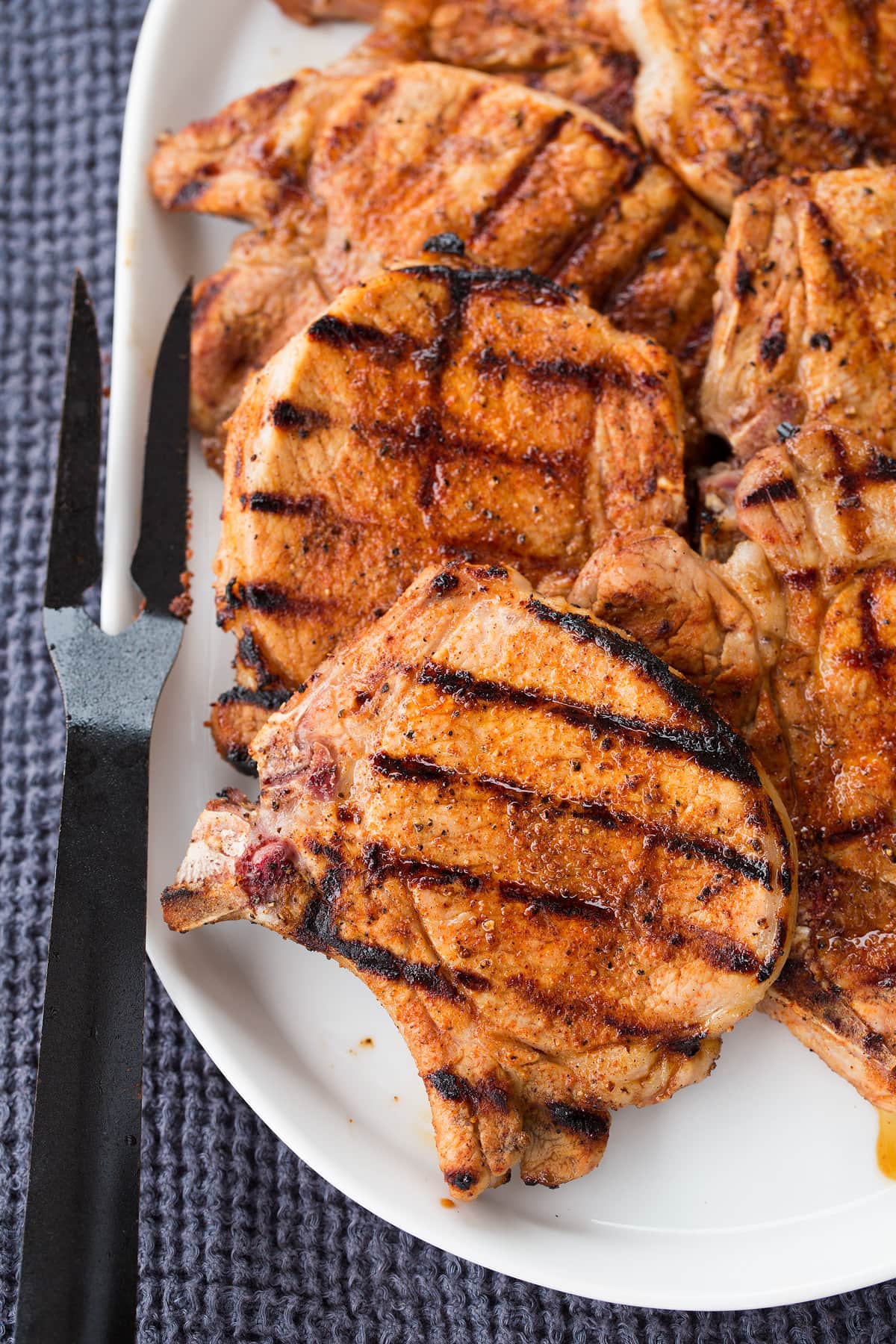 Grilled pork chops on a white oval platter.