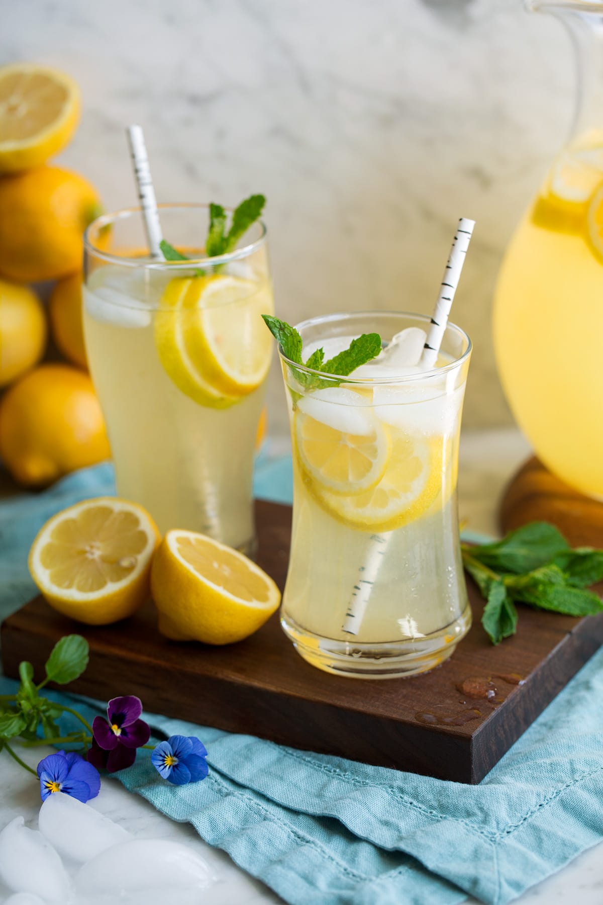 Two glasses of lemonade on a wooden platter.