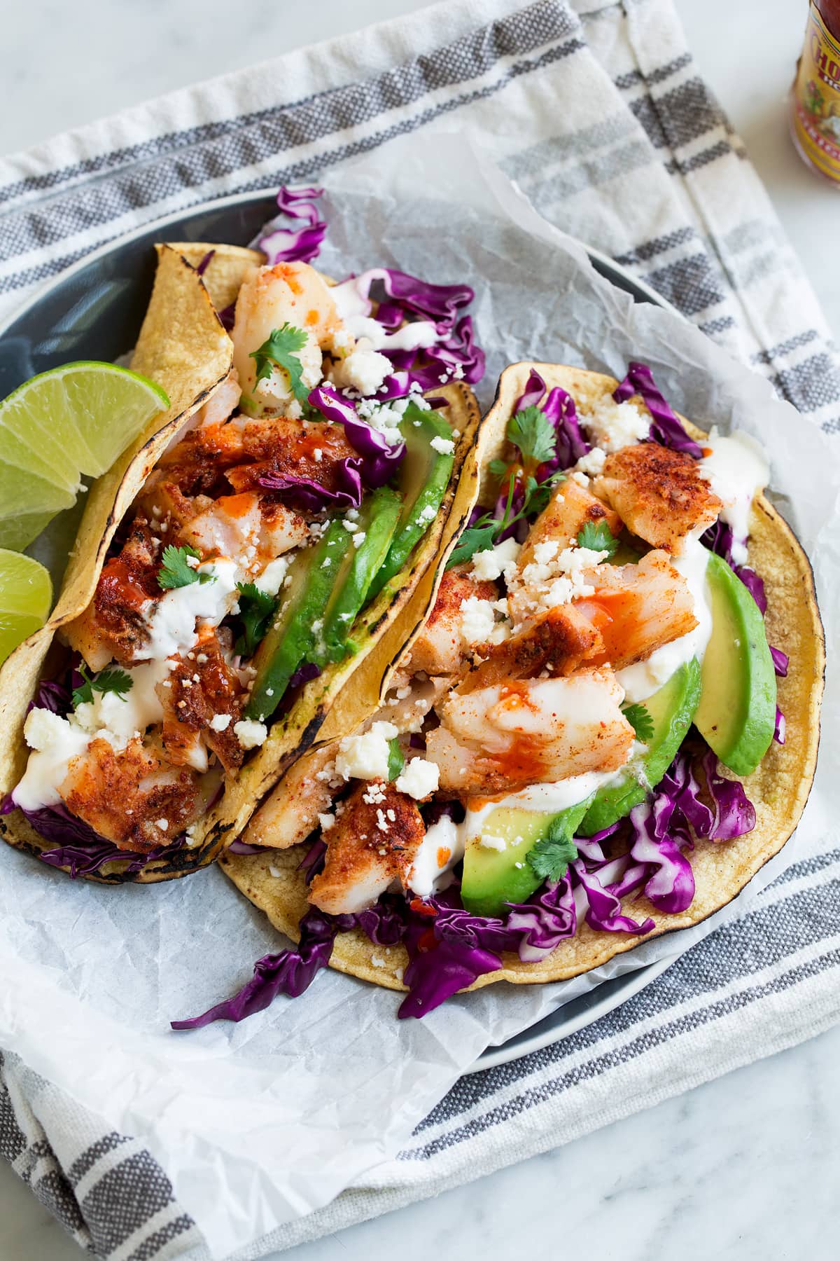 Two fish tacos on parchment paper on a plate.