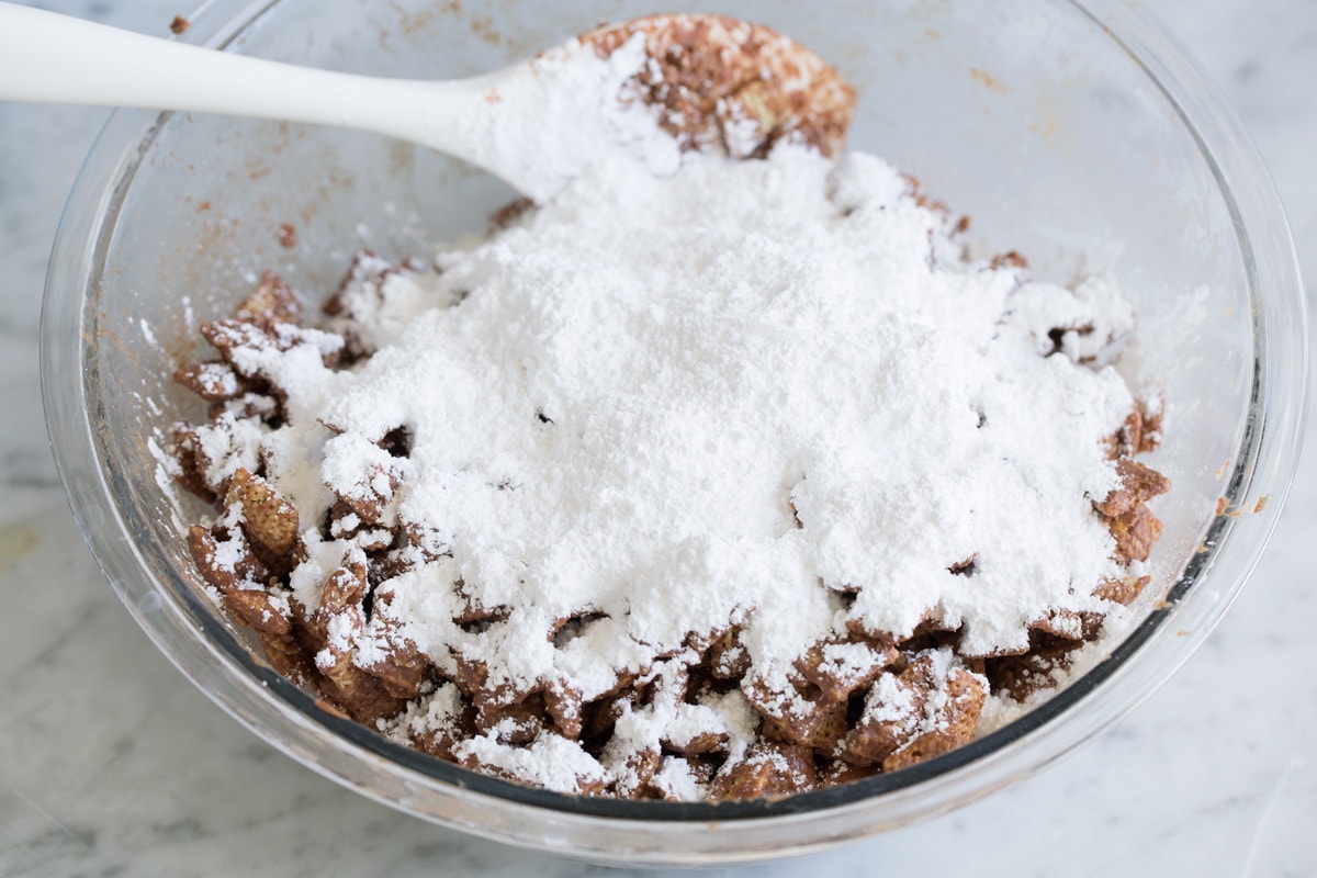 Adding powdered sugar to puppy chow mixture.