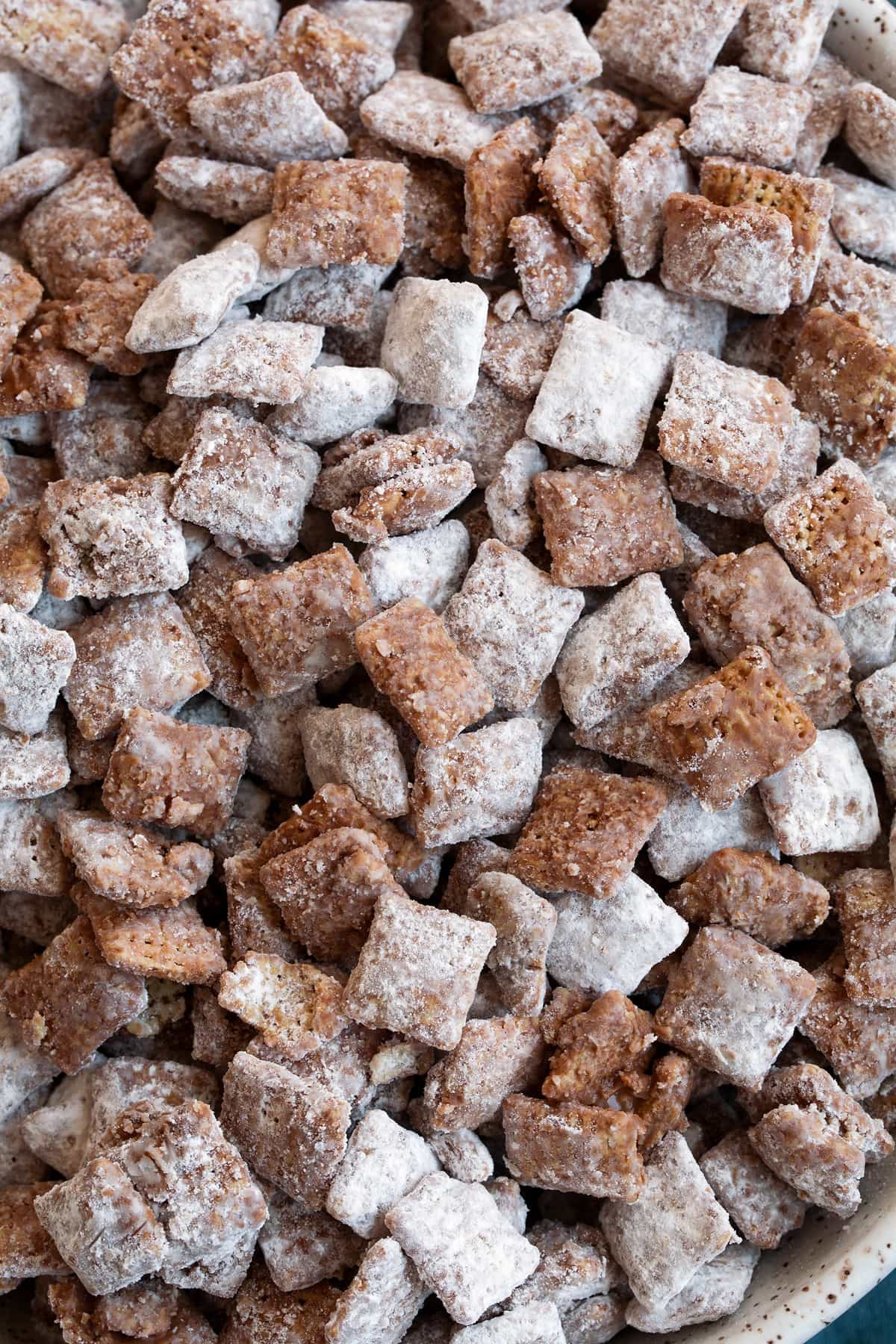 Close up image of muddy buddies showing texture of chocolate coating, powdered sugar and cereal.