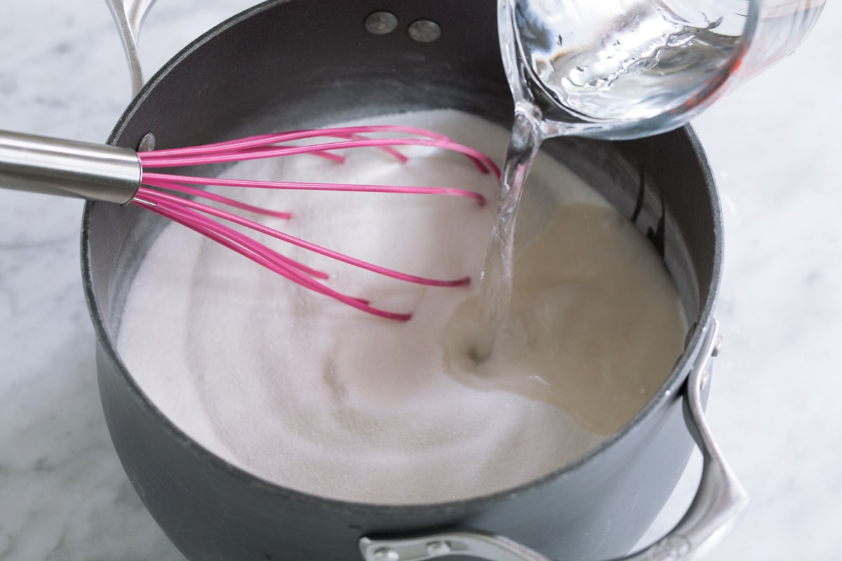 Pouring water into sugar and pectin mixture in pot.