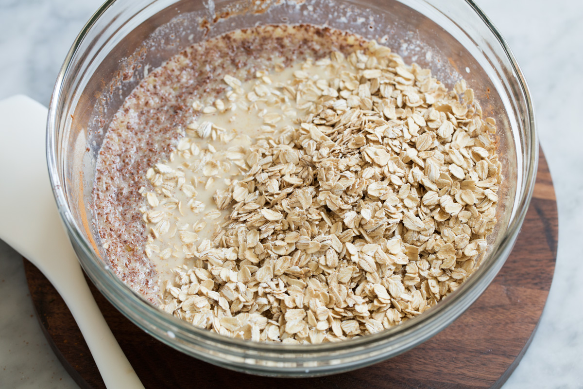 Mixing oats into liquid mixture in glass mixing bowl.