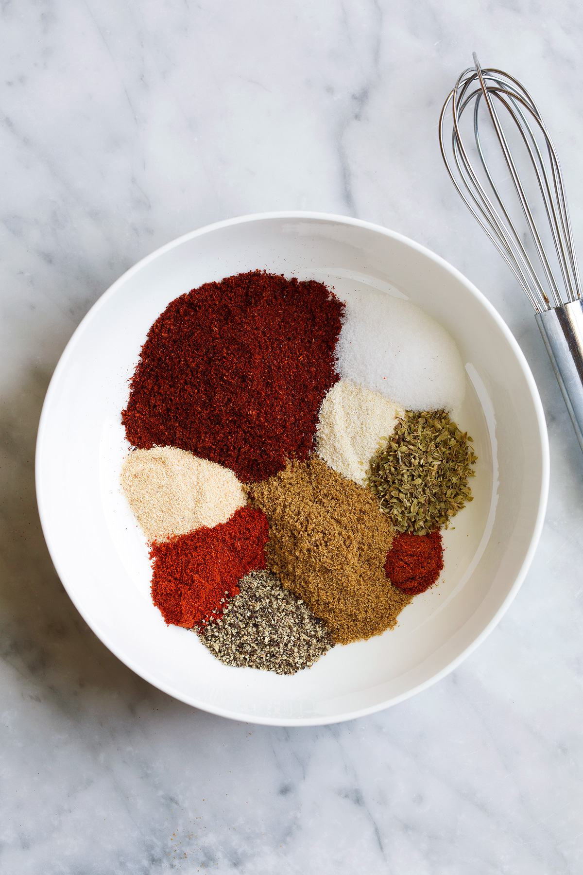 Taco seasoning in a mixing bowl showing all the spices separately before mixing.