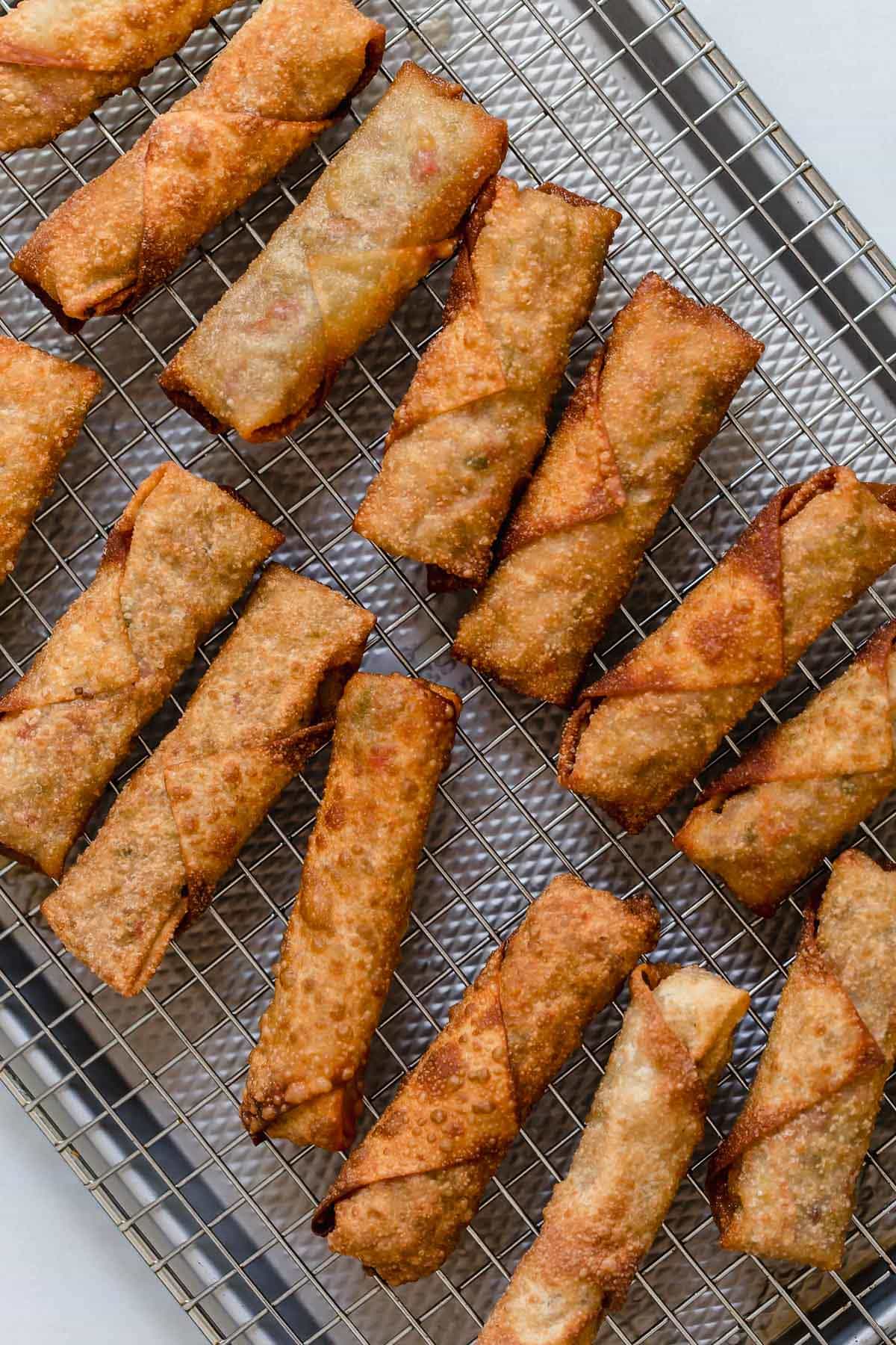 Egg rolls on a cooling rack set over a baking sheet.