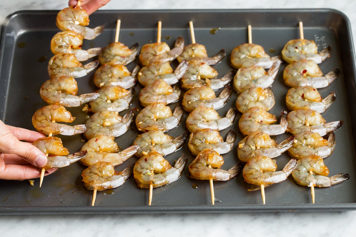 Showing how to thread shrimp onto wooden skewers.