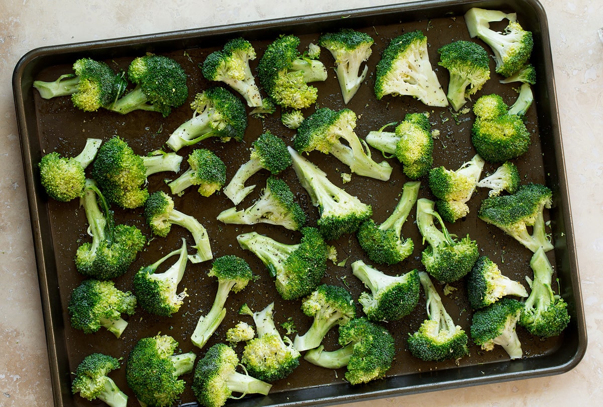 Raw boccoli florets on a baking sheet before baking.
