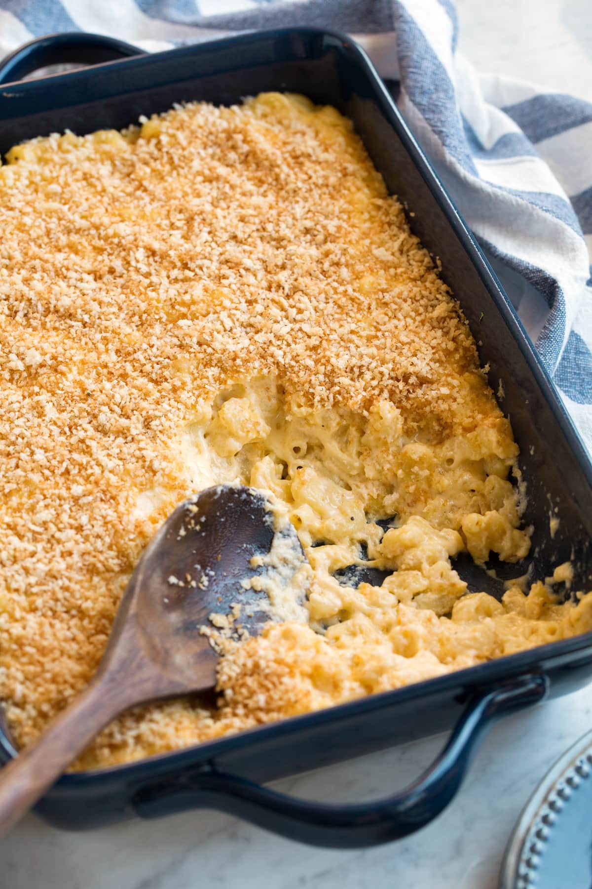 Baked macaroni in a casserole dish with a few scoops removed to show creamy cheesy macaroni noodles.