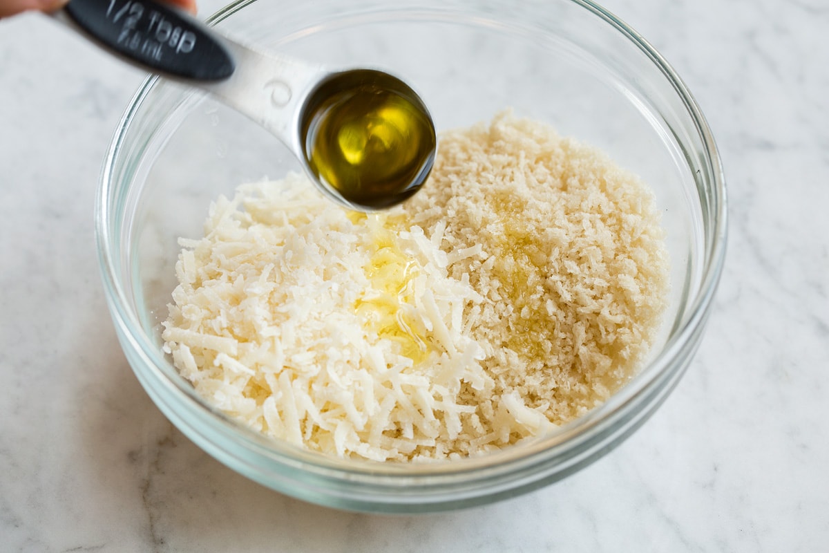 Preparing the panko mixture for stuffed mushrooms in a glass mixing bowl and drizzling with olive oil.
