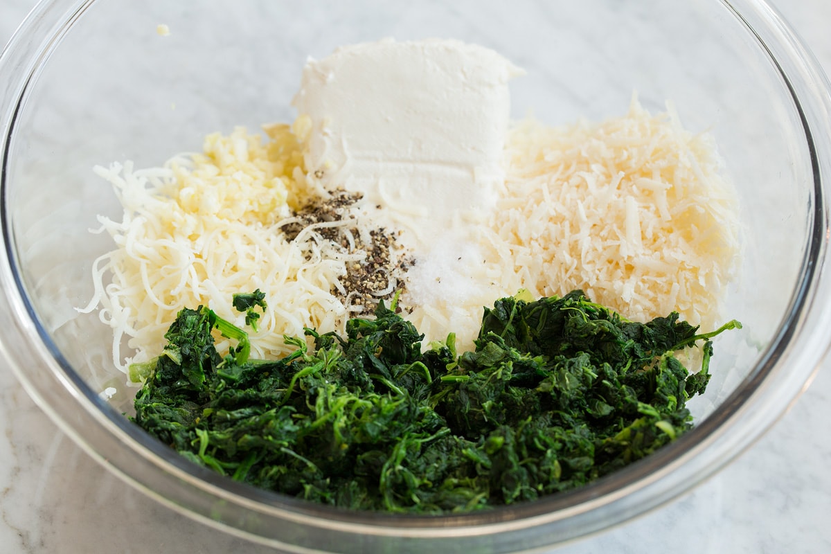 Second step of making stuffed mushrooms shown here, mixing the cheeses and spinach in a mixing bowl.