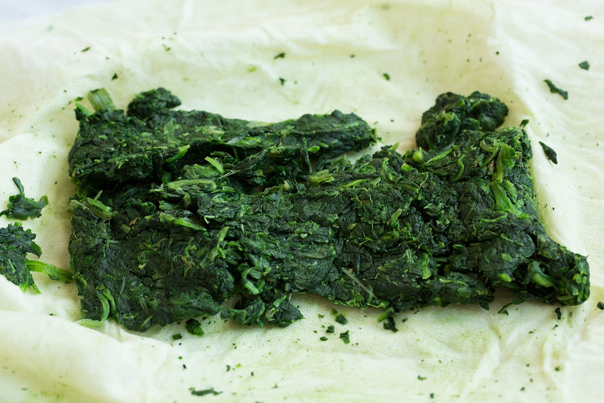 Spinach on paper towels shown after squeezing out the excess moisture. The first step to make stuffed mushrooms.