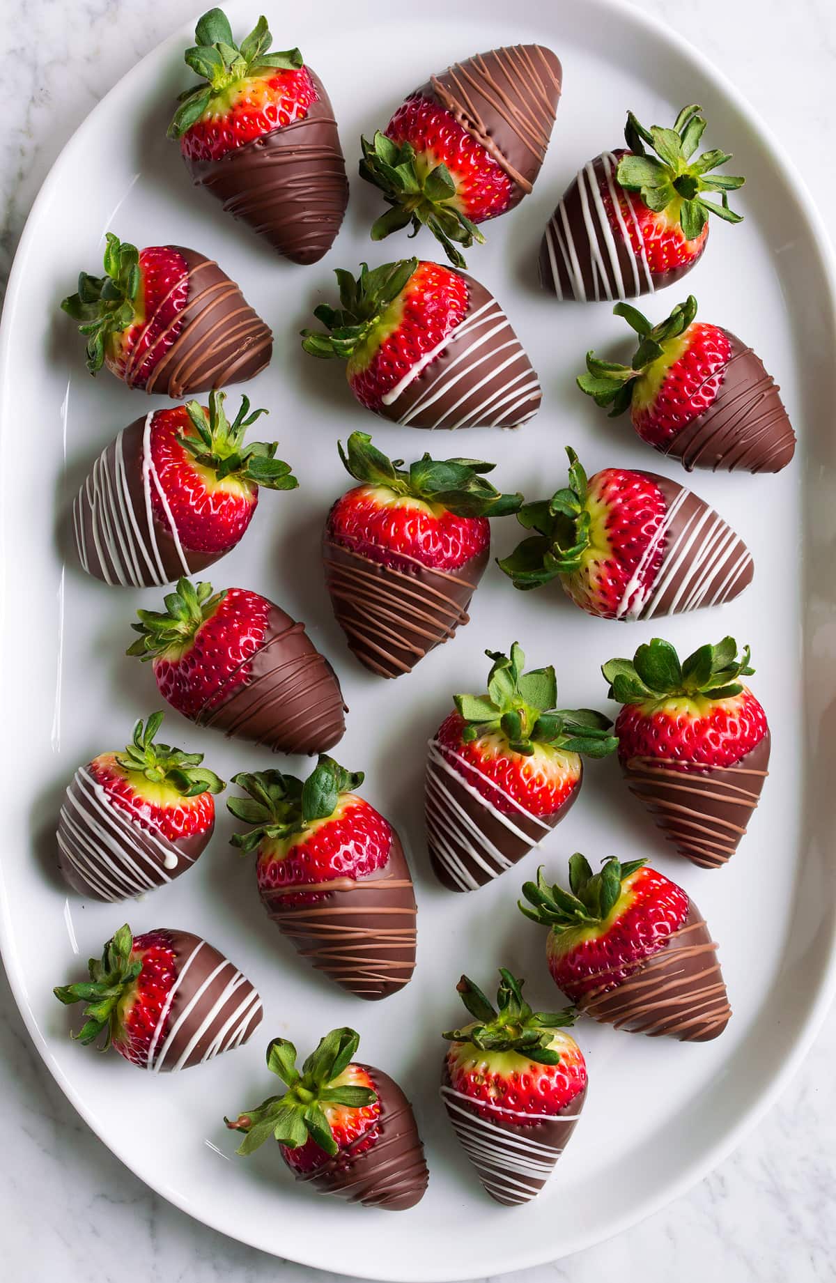 Chocolate dipped strawberries on an oval white platter.