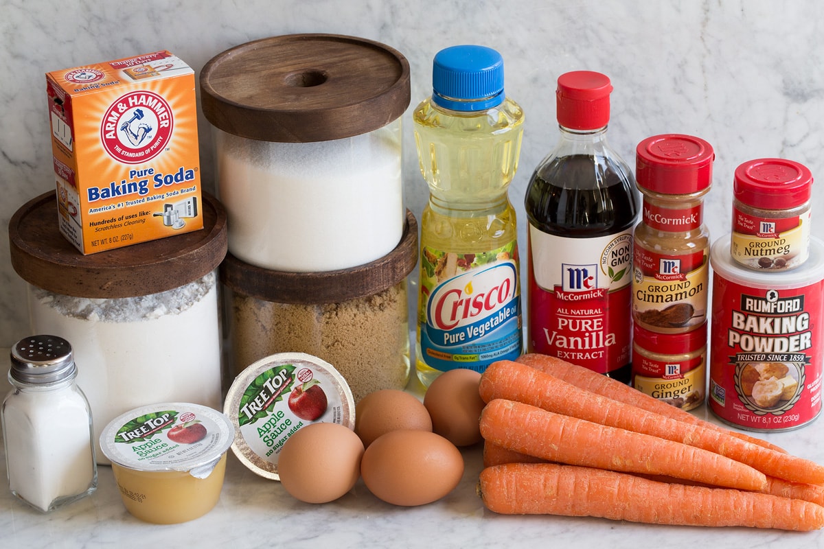 Ingredients that are used to make carrot cake shown here including salt, flour, white sugar, brown sugar, applesauce, baking soda, eggs, carrots, vegetable oil, vanilla, cinnamon, nutmeg, ginger and baking powder.