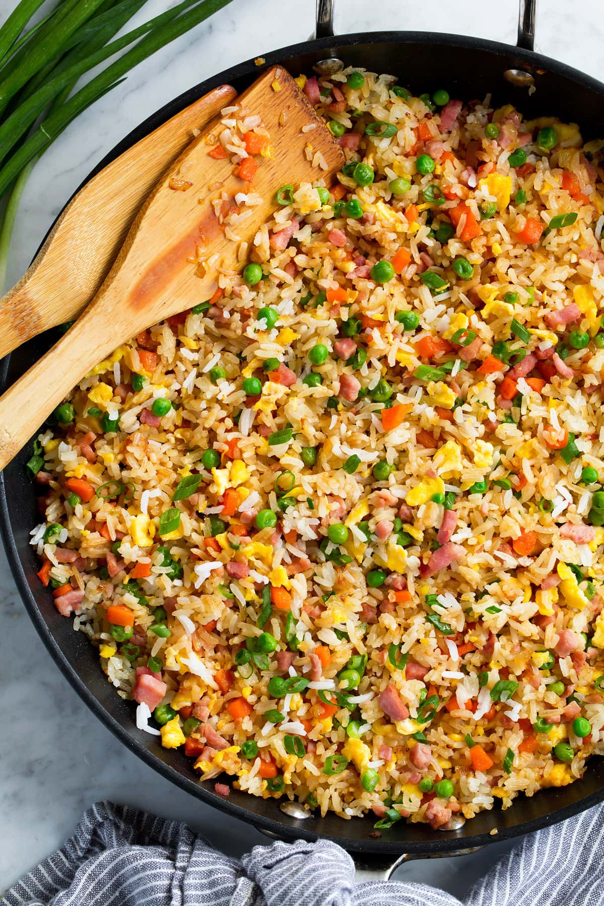 Close up image of rice rice in a skillet with bamboo serving spoons.